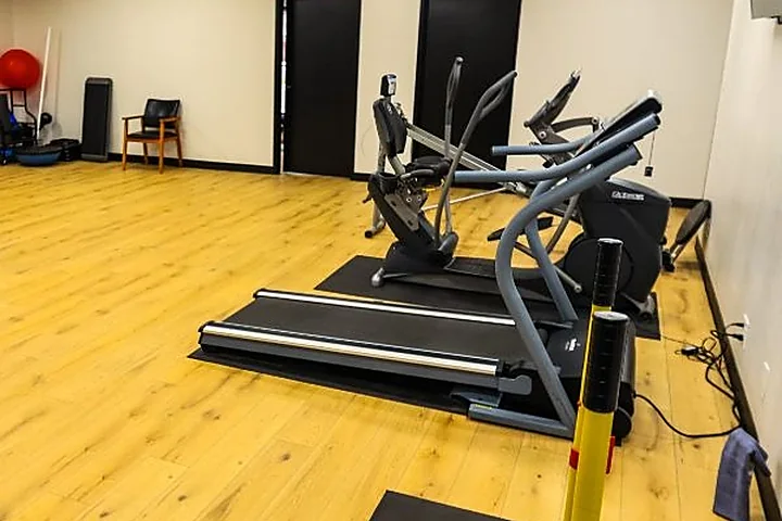 A treadmill beside the open wood-floor training area at Cultivate Wellness & Sports Rehab in Midland