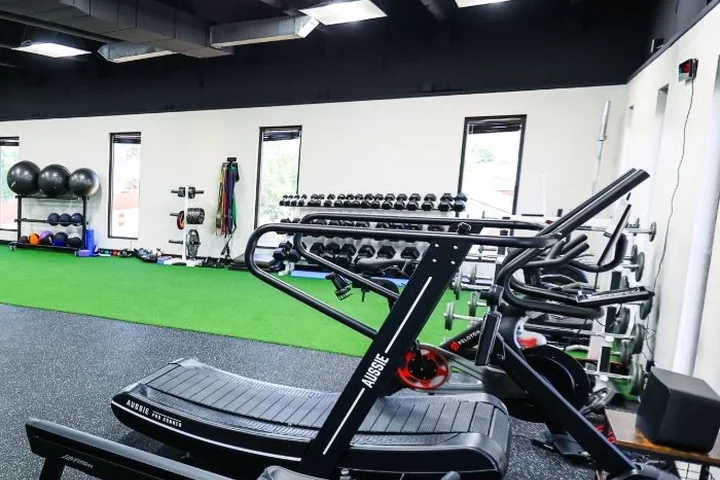 A turf training strip with a weighted sled and dumbbells at Cultivate Wellness & Sports Rehab